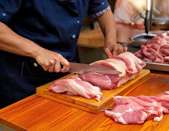 Firefly female worker is slicing pork for customers on wooden board hands only closeup side view-Putino-Food